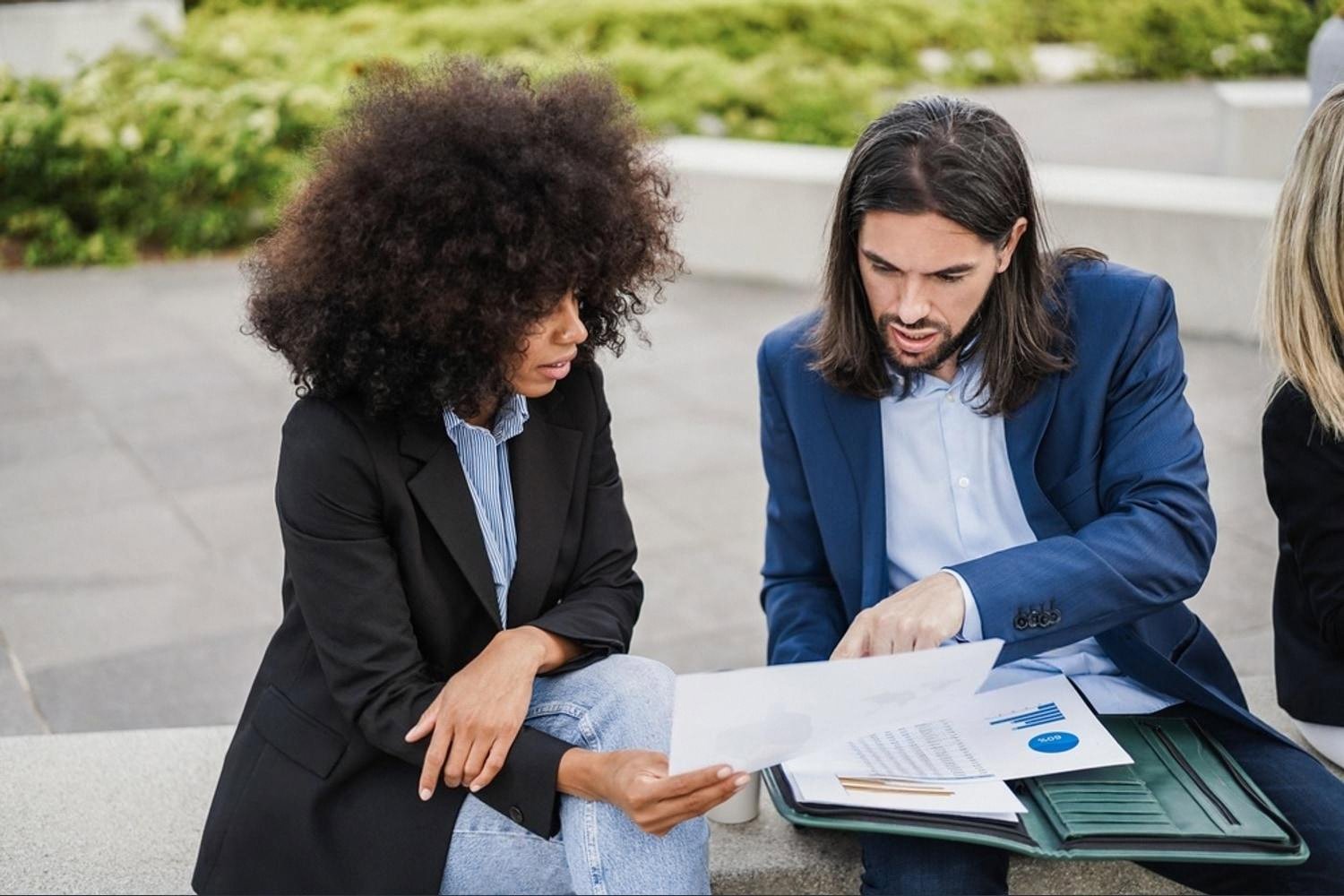 Two young professionals reviewing a business report outdoors in Dubai